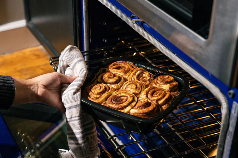 Image of hand pulling out of the oven, Xtrema's cake pan with cinnamon rolls.