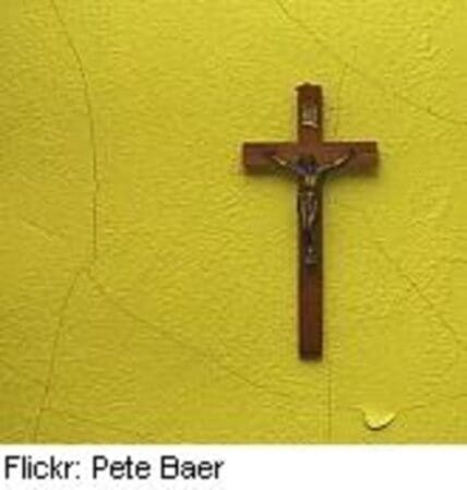 Wooden crucifix mounted on a bright yellow wall