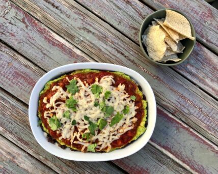Image of healthy Vegetarian vegan 5 layer black ben dip on a table served with a small bowl of tortilla chips. It's the healthiest 5 layer bean dip ever via Organic Authority