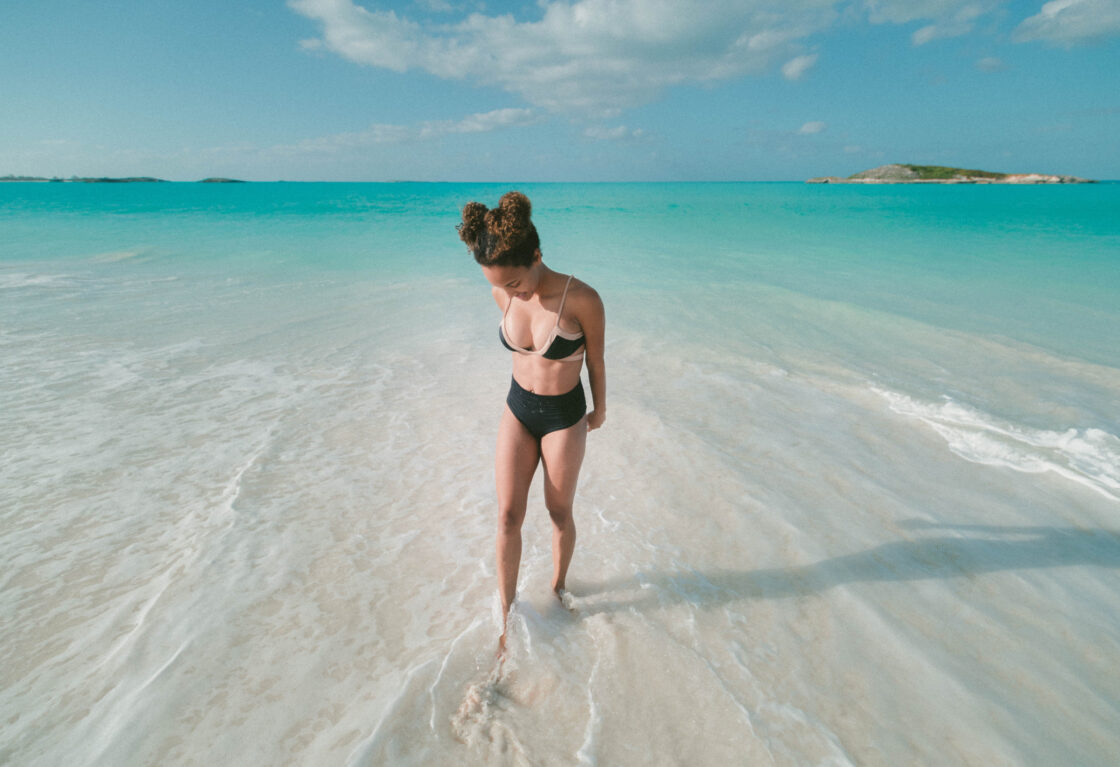 Woman wearing bikini standing in blue water considering marine collagen benefits.