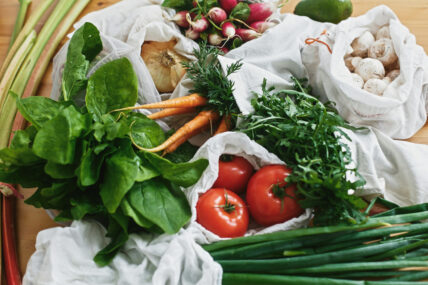 Image of fresh produce: tomatoes, carrots, spinach, green onions, and mushrooms some are part of the Daily Dozen 2024 or the Clean 15. These lists help you choose the right produce in your grocery store to keep toxins out of your system.