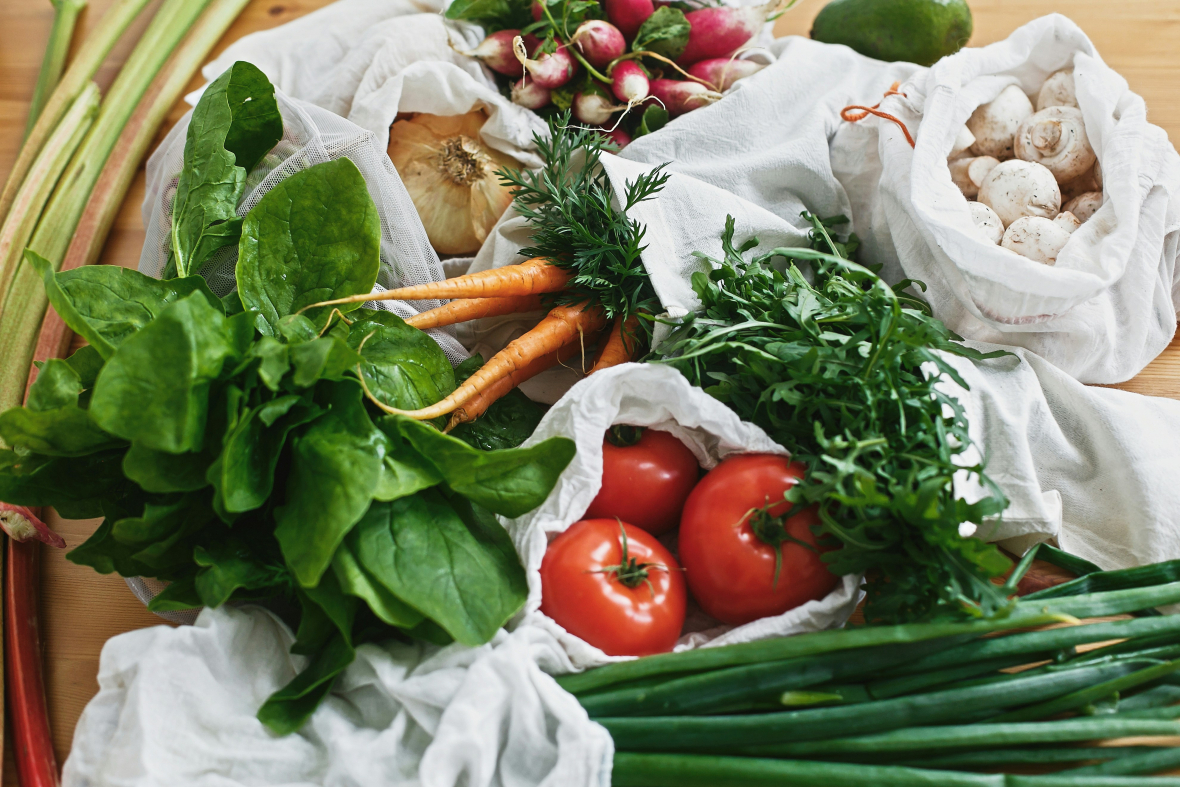 Image of fresh produce: tomatoes, carrots, spinach, green onions, and mushrooms some are part of the Daily Dozen 2024 or the Clean 15. These lists help you choose the right produce in your grocery store to keep toxins out of your system.