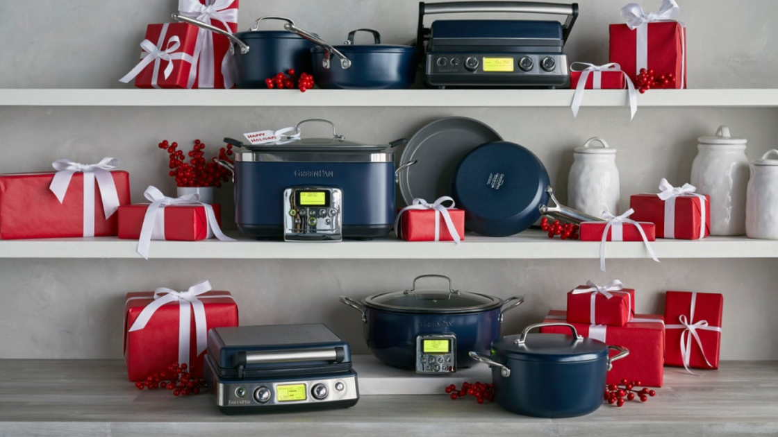 Image of GreenPan products, all in Oxford blue, displayed on a counter and two white shelves above and styled with gift boxes wrapped in red paper and white ribbons showing the best gift options for the holiday season.