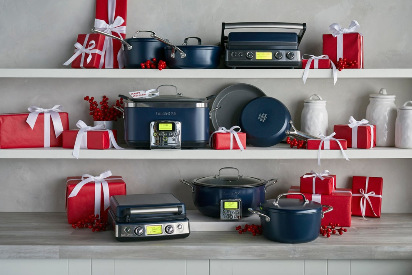 Image of GreenPan products, all in Oxford blue, displayed on a counter and two white shelves above and styled with gift boxes wrapped in red paper and white ribbons showing the best gift options for the holiday season.