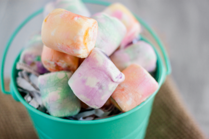 Image of colorfully dyed vegan marshmallows in a teal bucket. This invites you to learn how to dye marshmallows for Easter or for any fun holiday for which you want to add some color.