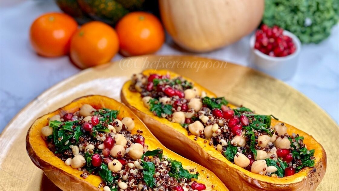 vegetarian stuffed butternut squash on a gold charger with clementines, squash, pomegranate arils, and kale in the backgroud.