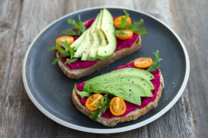 Avocado and beet humus on toast with cherry tomatoes and arugula