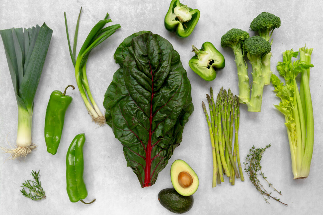 Image of green vegetables such as asparagus, celery, bell pepper and chard, laid out on countertop surface showing where liquid chlorophyll comes from via Organic Authority