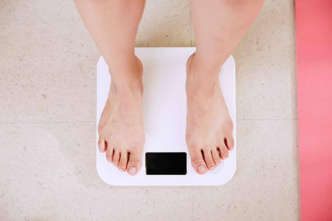 Image of woman's feet standing on white digital scale on terrazzo tiled floor posing the question if the health benefits of liquid chlorophyll extend to weight loss via Organic Authority.