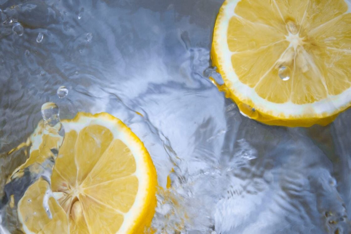 Image of lemons floating in water, vitamin C is a natural, and potent, skin serum ingredient that helps brighten skin, via Organic Authority.