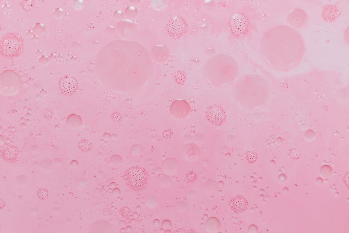 Image of light pink oily liquid up close to surface showing bubbles for clean face serums made of natural ingredients.