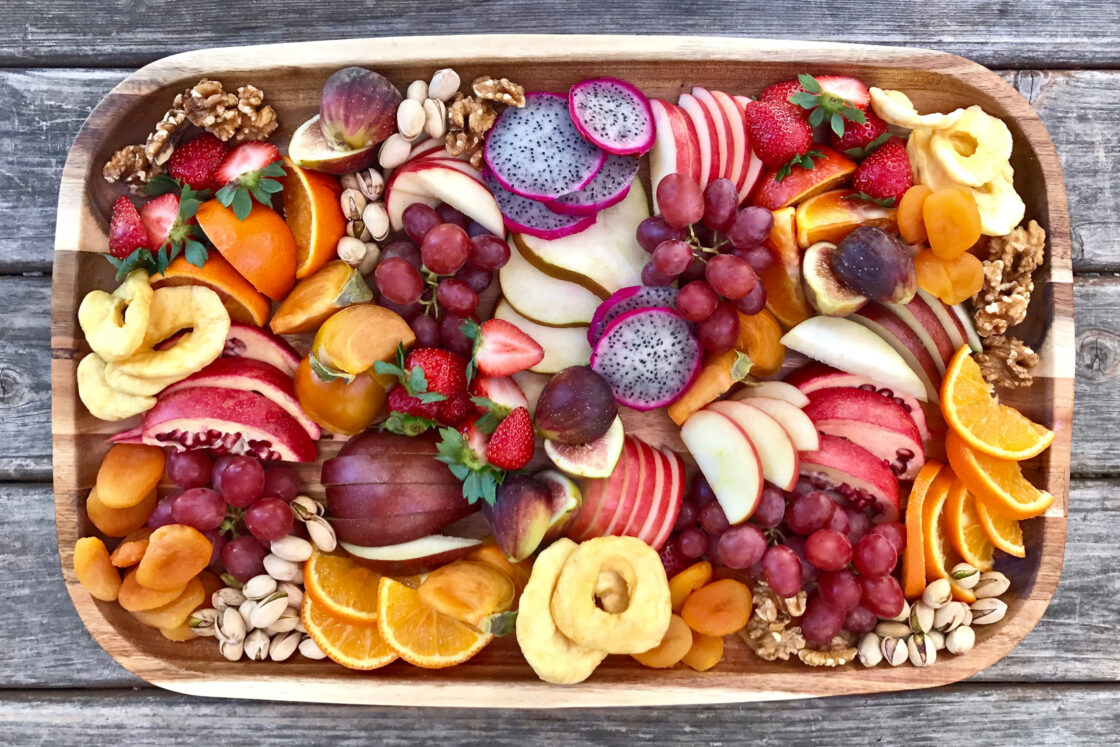 The hormone insulin in women regulates blood sugar - Colorful fruit platter with dragonfruit, apple, strawberry, oranges, grapes, and walnuts.
