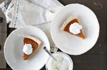 Image of paleo pumpkin pie slices with whip cream on two white plates.