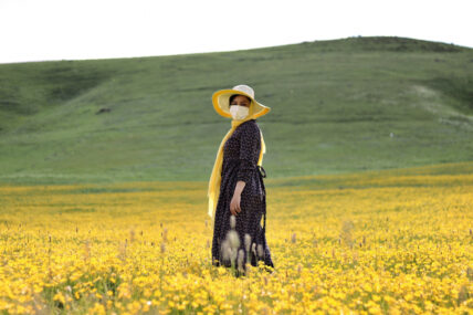 woman standing in field with yellow flowers wearing COVID-19 face mask in Ardabil Privince, Iran