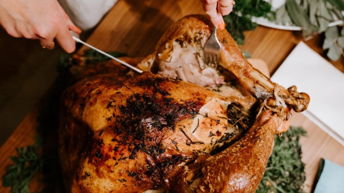 Image of a cooked turkey on a cutting board and someone slicing into it. More people are choosing heritage turkeys for their Thanksgiving meals.