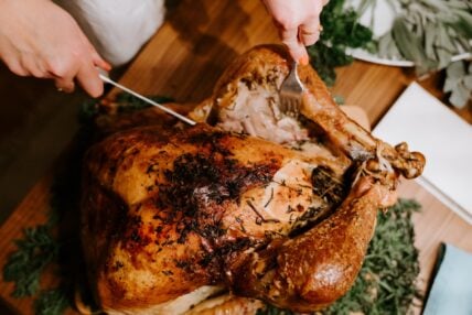 Image of a cooked turkey on a cutting board and someone slicing into it. More people are choosing heritage turkeys for their Thanksgiving meals.