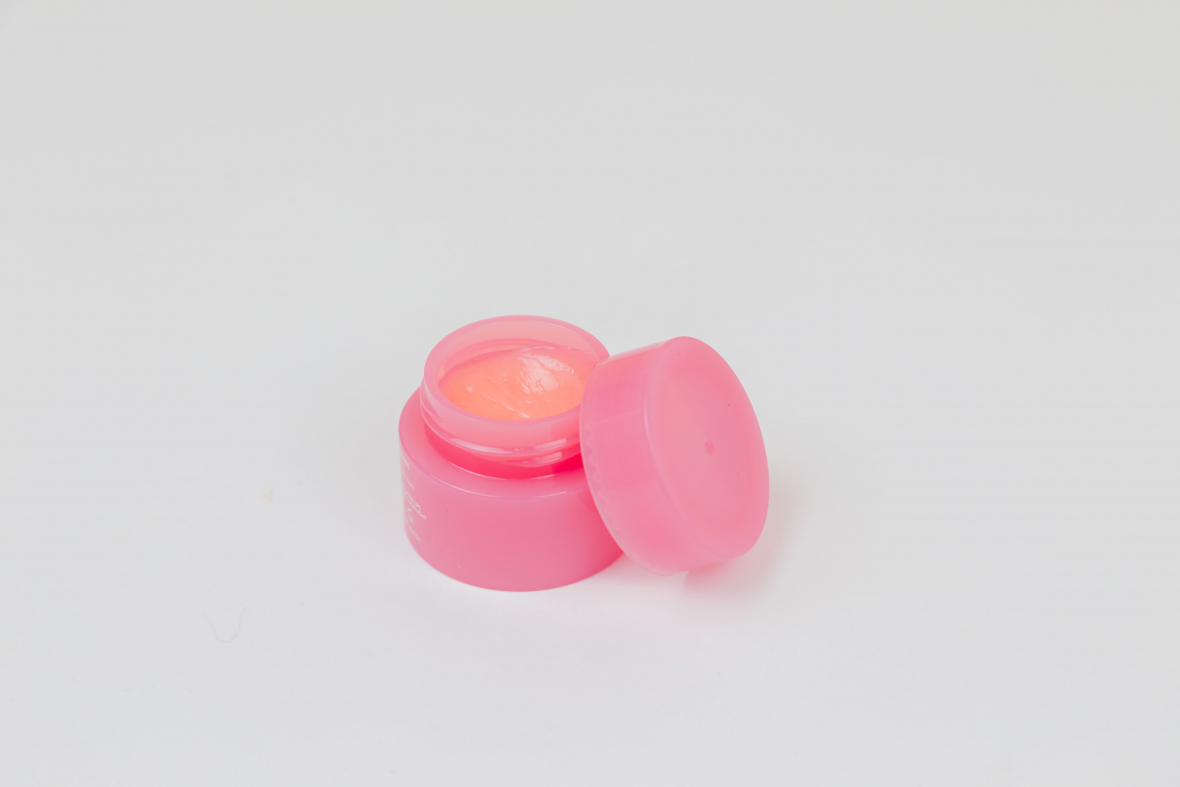 Image of vaseline alternative lip balm in small pink pot with lid set askew showcasing petroleum jelly alternatives.