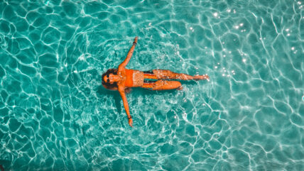 woman wearing sunglasses floating in pool on back