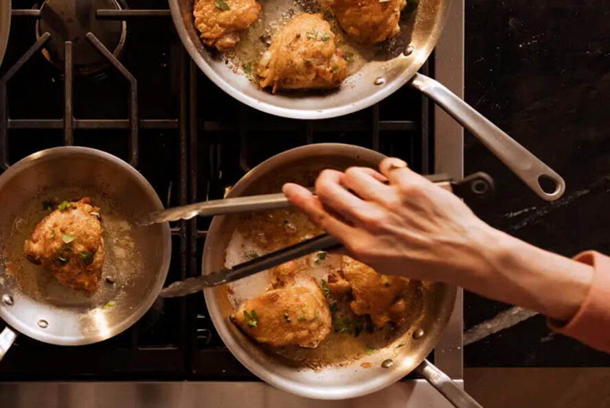 Image of a hand reaching over to flip over a pakora sizzling in a Made In stainless steel pan.