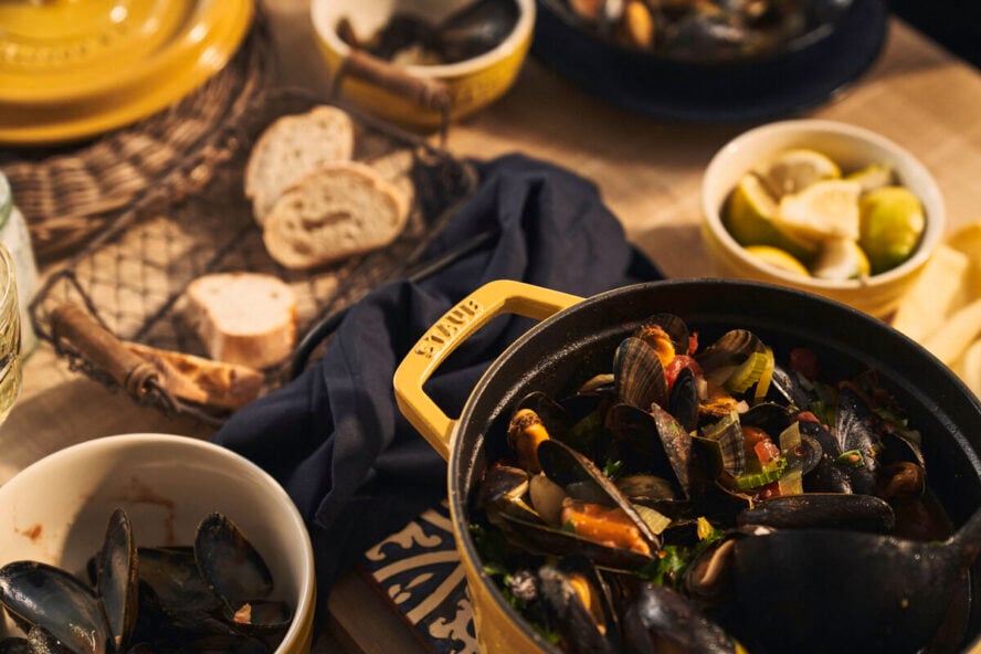 Image of a Staub enameled cast iron cocotte in the citron colorway, full of mussels.
