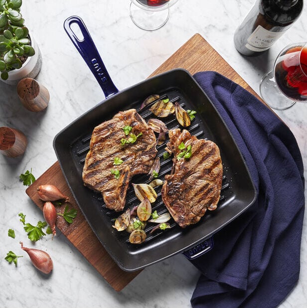 Image of the Staub 12-inch Square Grill Pan in dark blue, with two steaks.