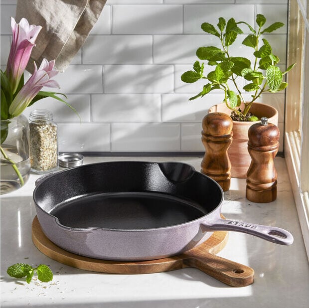 Image of the Staub 11-inch Traditional Deep Skillet in Lilac on a wooden cutting board.