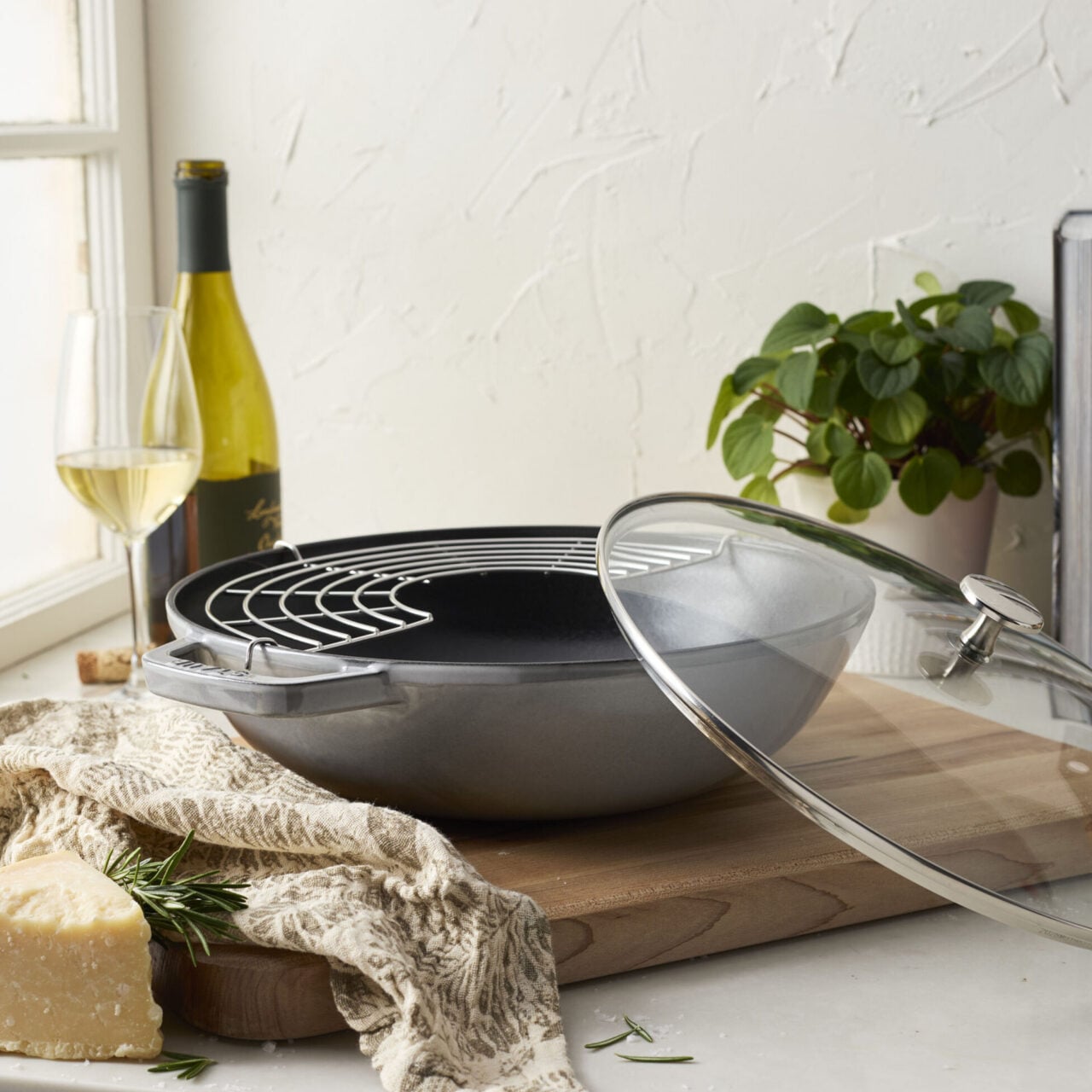 Image of the Staub 12-inch Perfect Pan in Graphite Grey, shown next to a bottle of white wine.