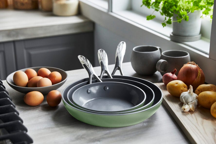 Image of the new GreenPan Valencia Pro ceramic nonstick frypan trio in Sage Green, shown on a counter next to a bowl of eggs.