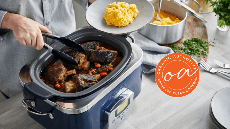 Image of the GreenPan Elite Slow Cooker in Oxford Blue, with a person using tongs to plate up slow cooked meat on top of mash directly from the cooker.