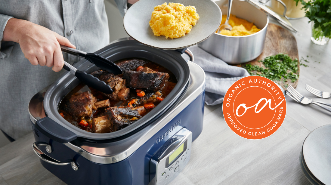 Image of the GreenPan Elite Slow Cooker in Oxford Blue, with a person using tongs to plate up slow cooked meat on top of mash directly from the cooker.