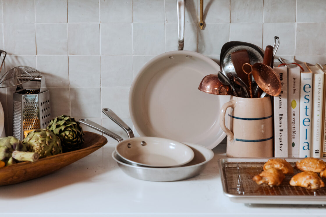 Image of a three piece frying pan set by Made In on a kitchen counter wiht utensils and a pan of freshly baked pastries.