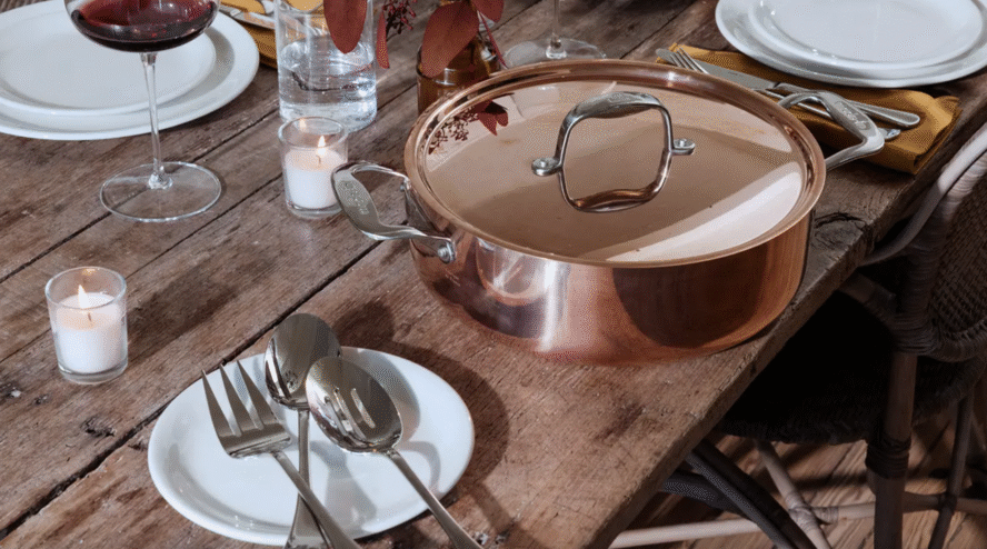 Image of a Made In copper pot on a wooden picnic table surrounded by plates.