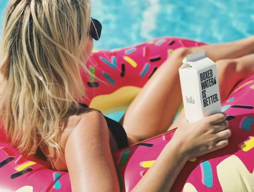 Image of woman floating in floaty in water, summer skin care.
