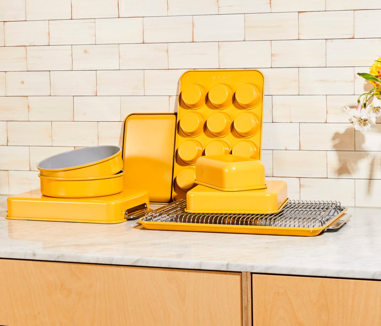 Image of the Caraway 11-piece bakeware set in a cheery yellow color (marigold), with the loaf pan prominently displayed.
