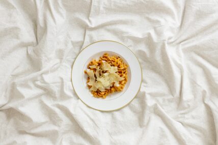 image of a bowl of pasta on a bed. Registered Dietitians suggest that what you eat before you go to bed, may affect your mood. what what you eat for midnight snacks