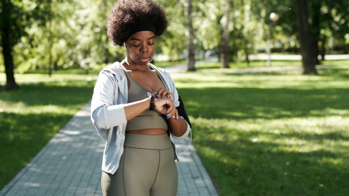 woman checking her heart rate while working out at a park doing a travel HIIT workout.