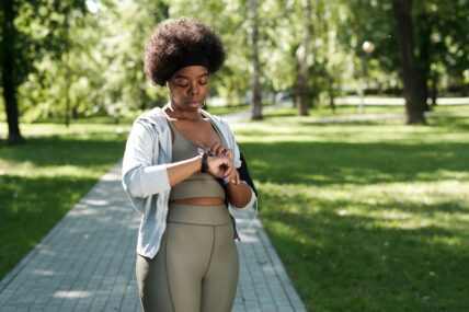 woman checking her heart rate while working out at a park doing a travel HIIT workout.