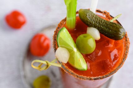 bloody mary mix recipe with lime, onion, olive, and pickle garnish from overhead view joanna stolowicz unsplash