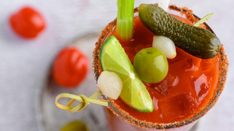 bloody mary mix recipe with lime, onion, olive, and pickle garnish from overhead view joanna stolowicz unsplash