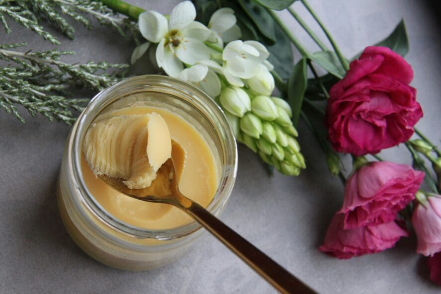 glass bowl of ghee surrounded by fresh flowers. Ghee is thought to tone the digestive tract and support the absorption of nutrients during a cleanse.