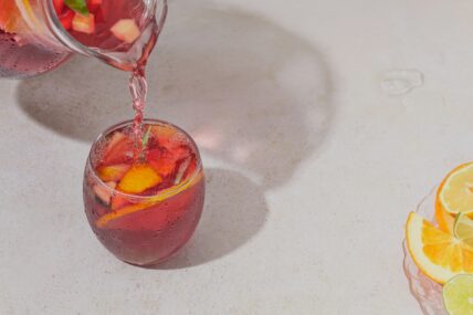 image of a pink sangria drink being poured into a glass with fruit garnish