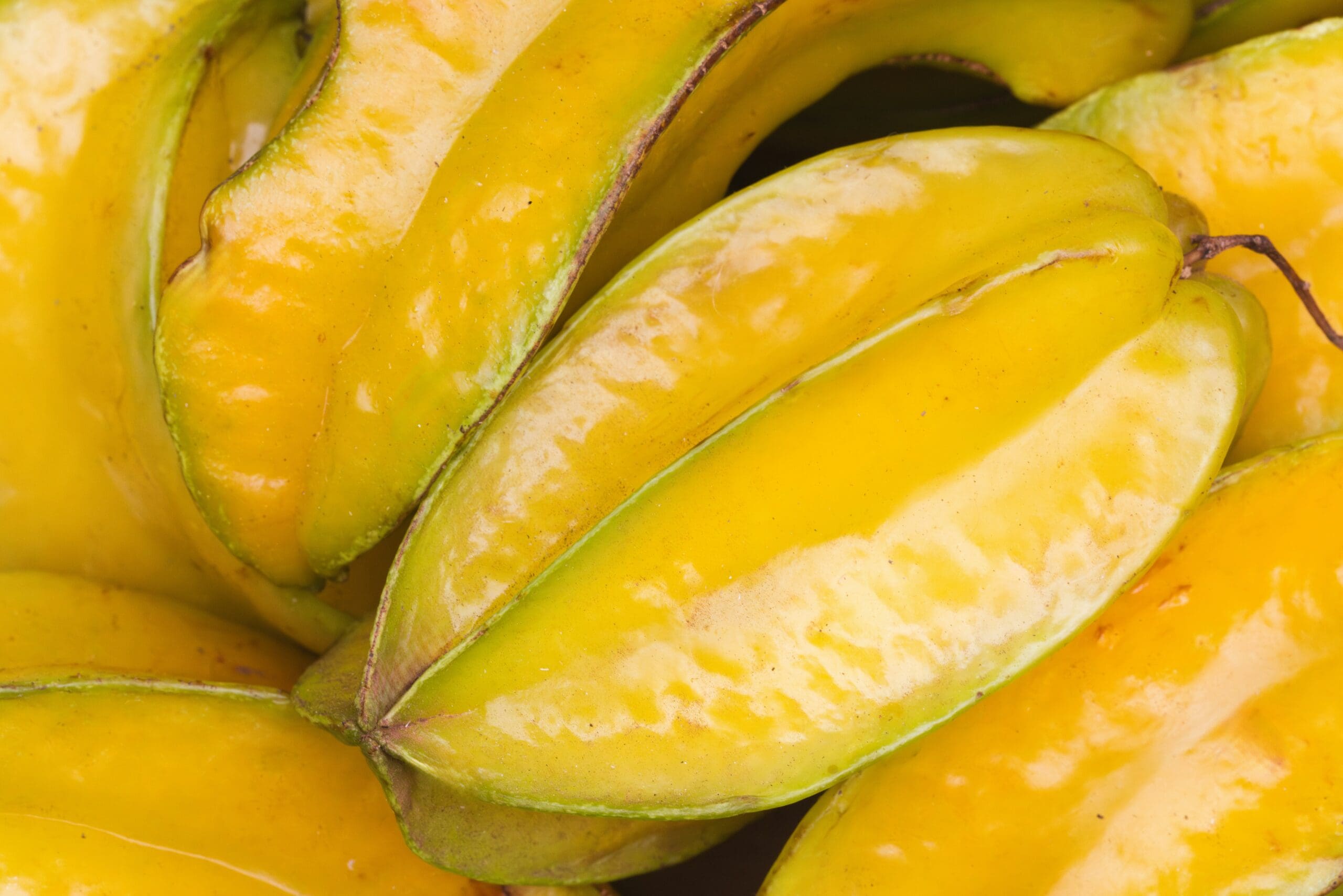 Upclose image of a pile of starfruit, which is an unusual fruit at the top of our list of unusual fruits and vegetables that you should try.