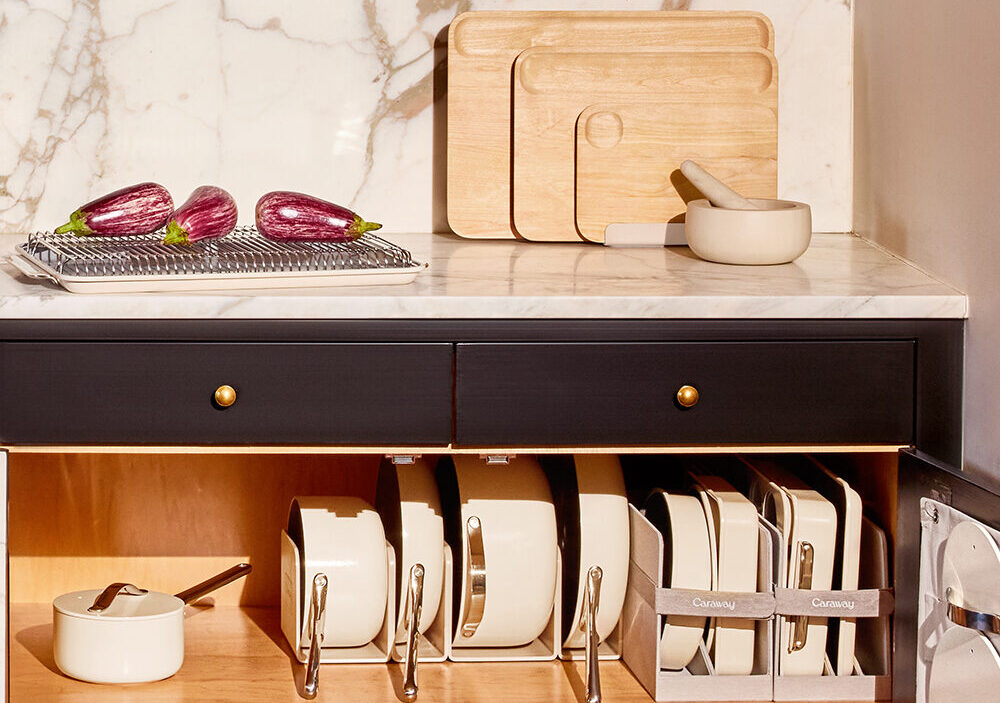 Image of many of the pieces in the Caraway Favorites Bundle stored neatly in a kitchen, from the Cookware Set to the Cutting Board Set.