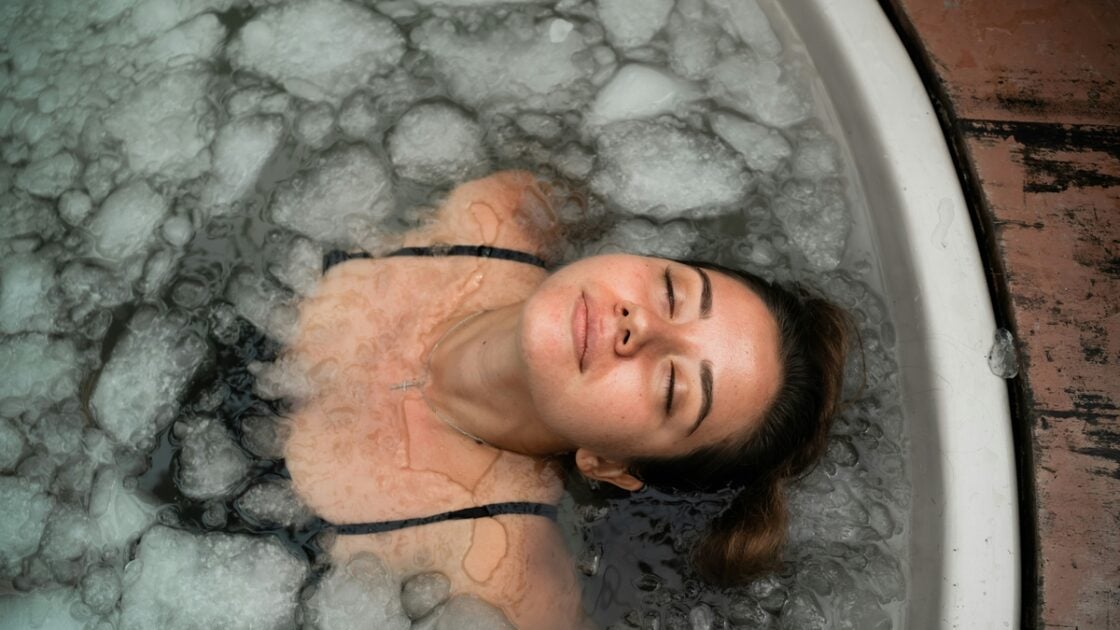 Image of a young woman with her eyes closed submerged in an ice bath.