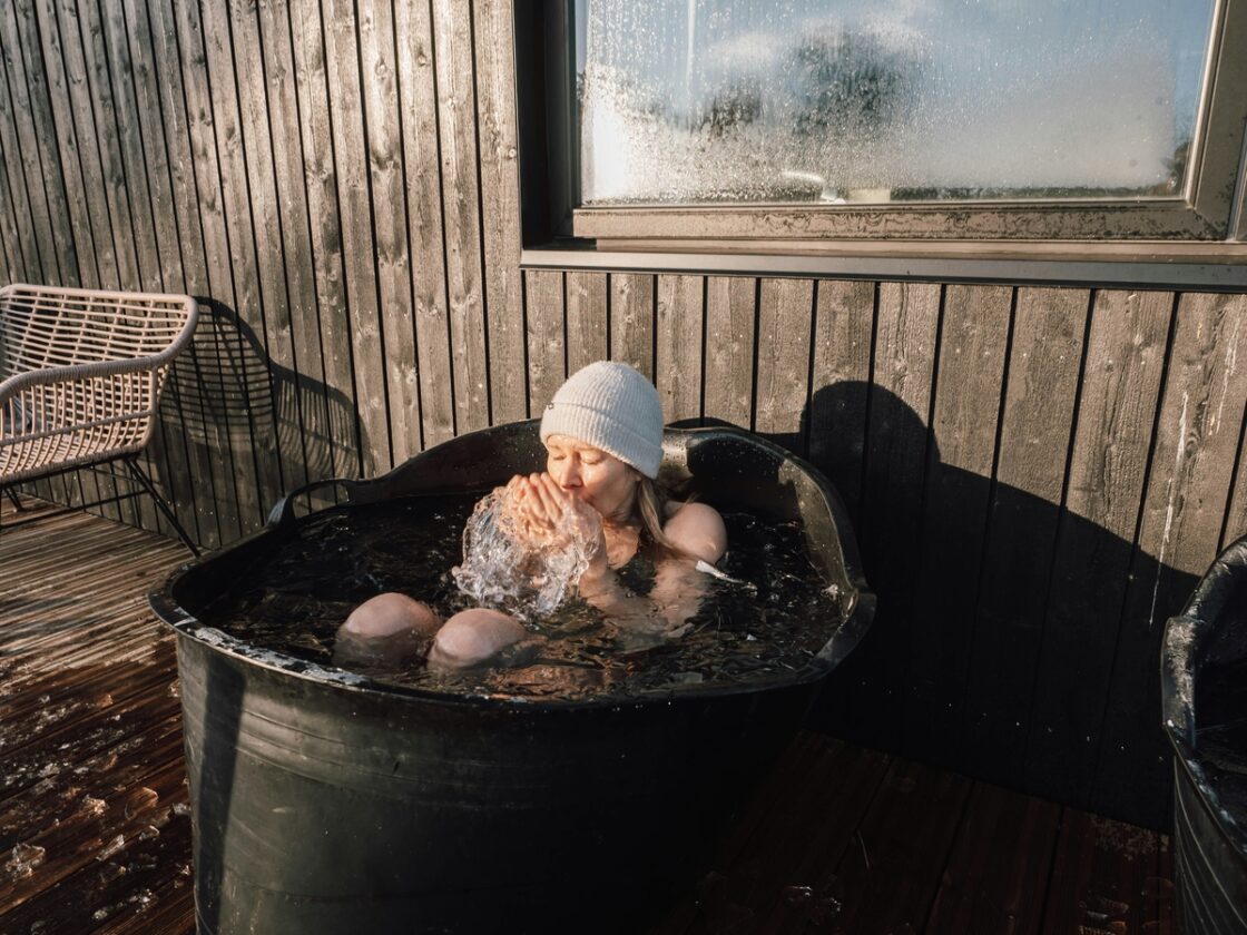 Image of a woman wearing a hat sitting with her arms crossed in an ice bath.