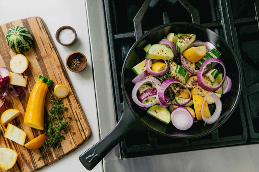 Image of an Xtrema pure ceramic black skillet on a stovetop filled with veggies