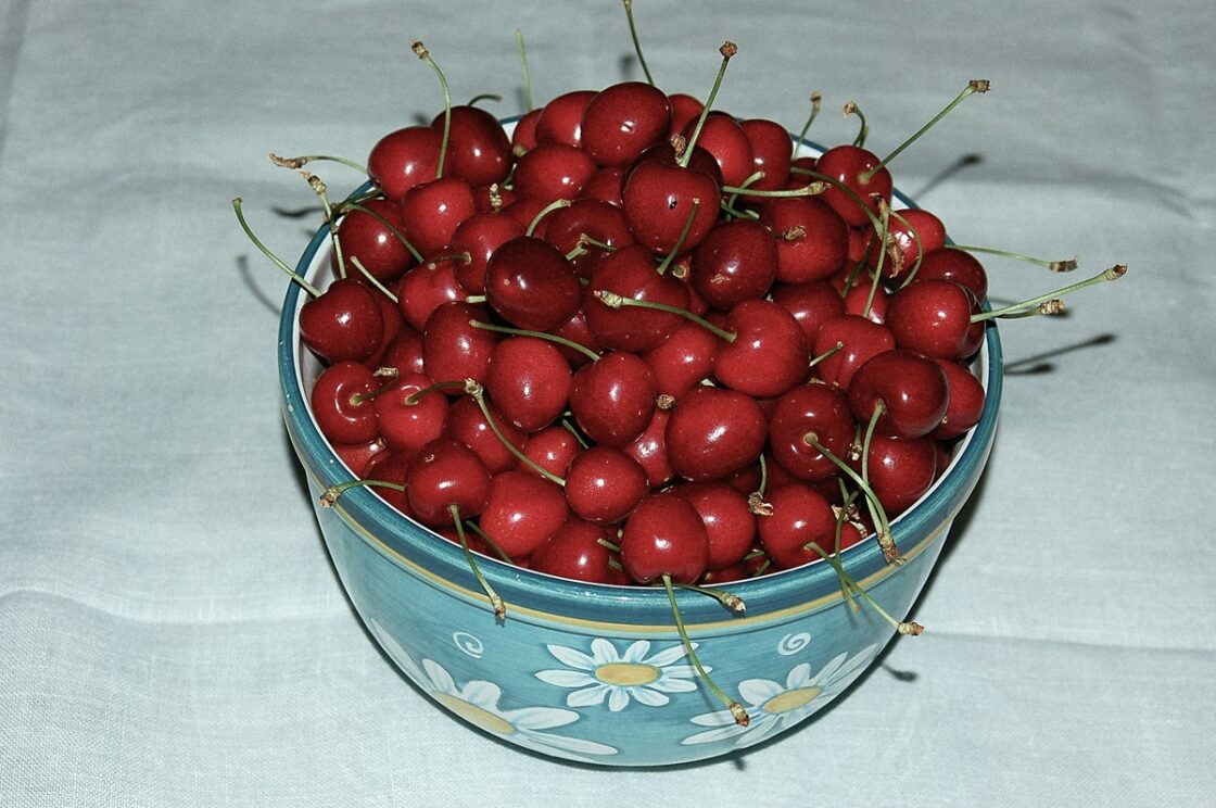 Image of a large blue bowl with a pattern of daisies, filled with tart sour cherries.