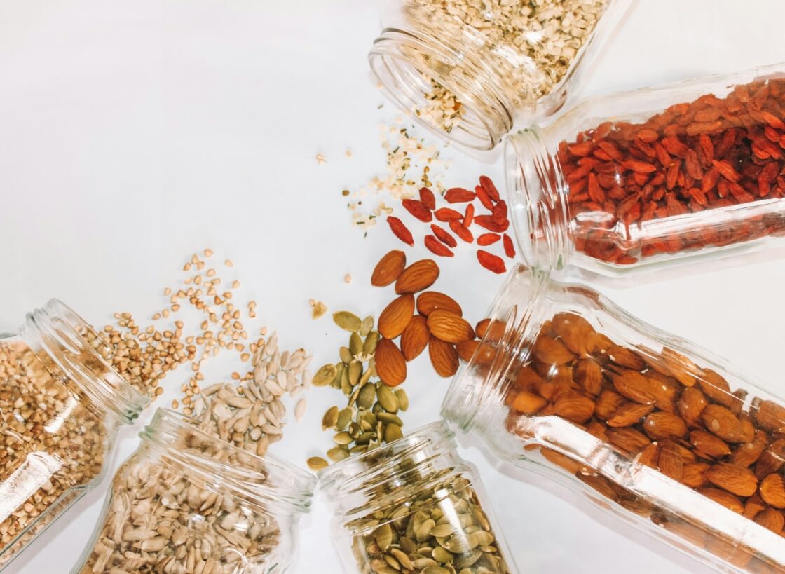 Image of a variety of several melatonin-rich foods spilling out of jars, including almonds, goji berries, and sunflower seeds.