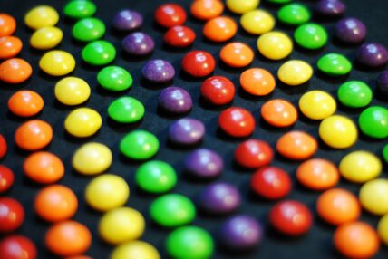Image of several rows of Skittles arranged in rainbow-ordered rows.