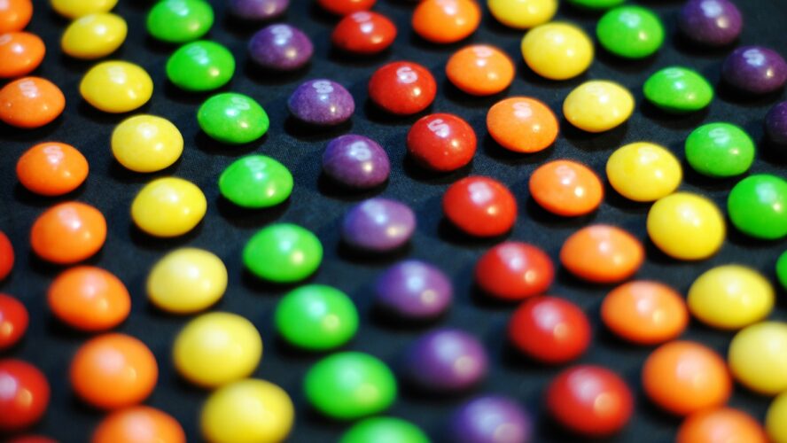Image of several rows of Skittles arranged in rainbow-ordered rows.